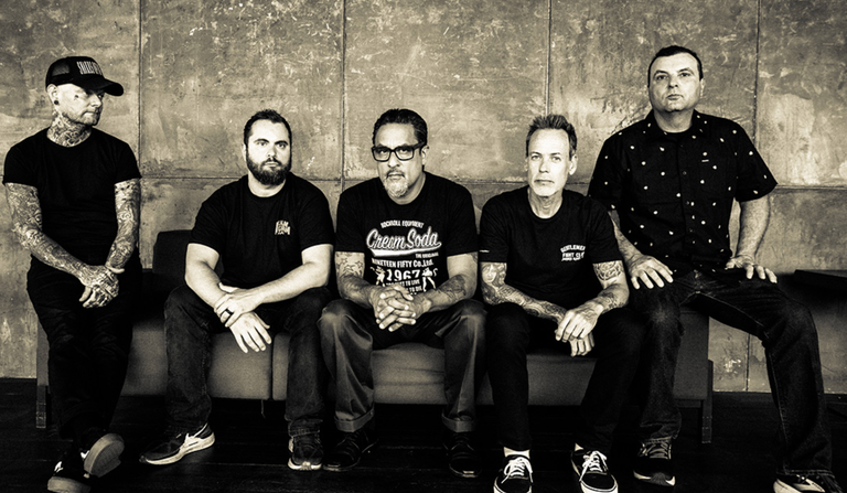 American punk rock band Strung Out members sitting together on a couch in a black and white promotional photo.